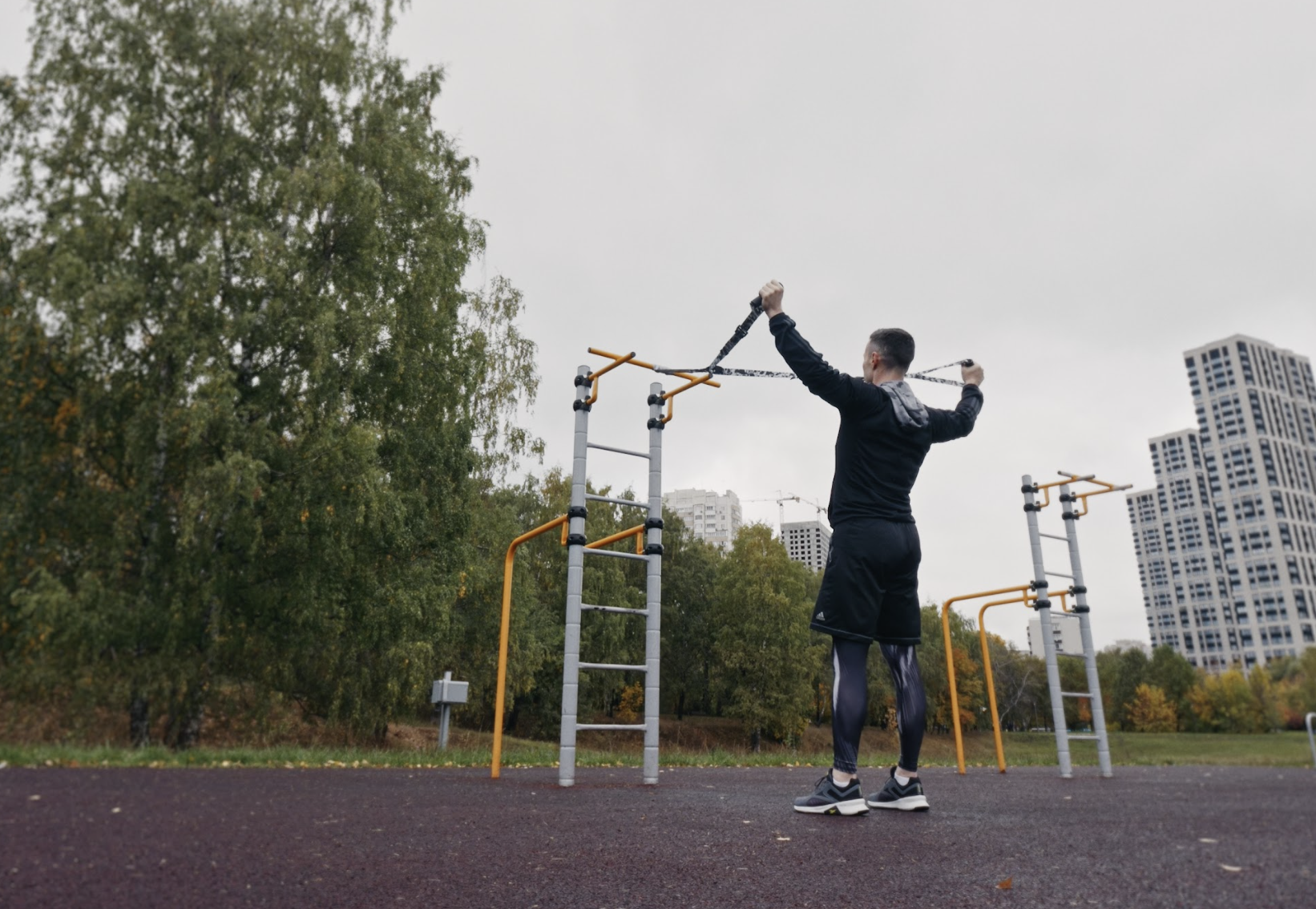 Мужчина Андрей Карпиков тренируется на спортивной площадке с тренировочными петлями